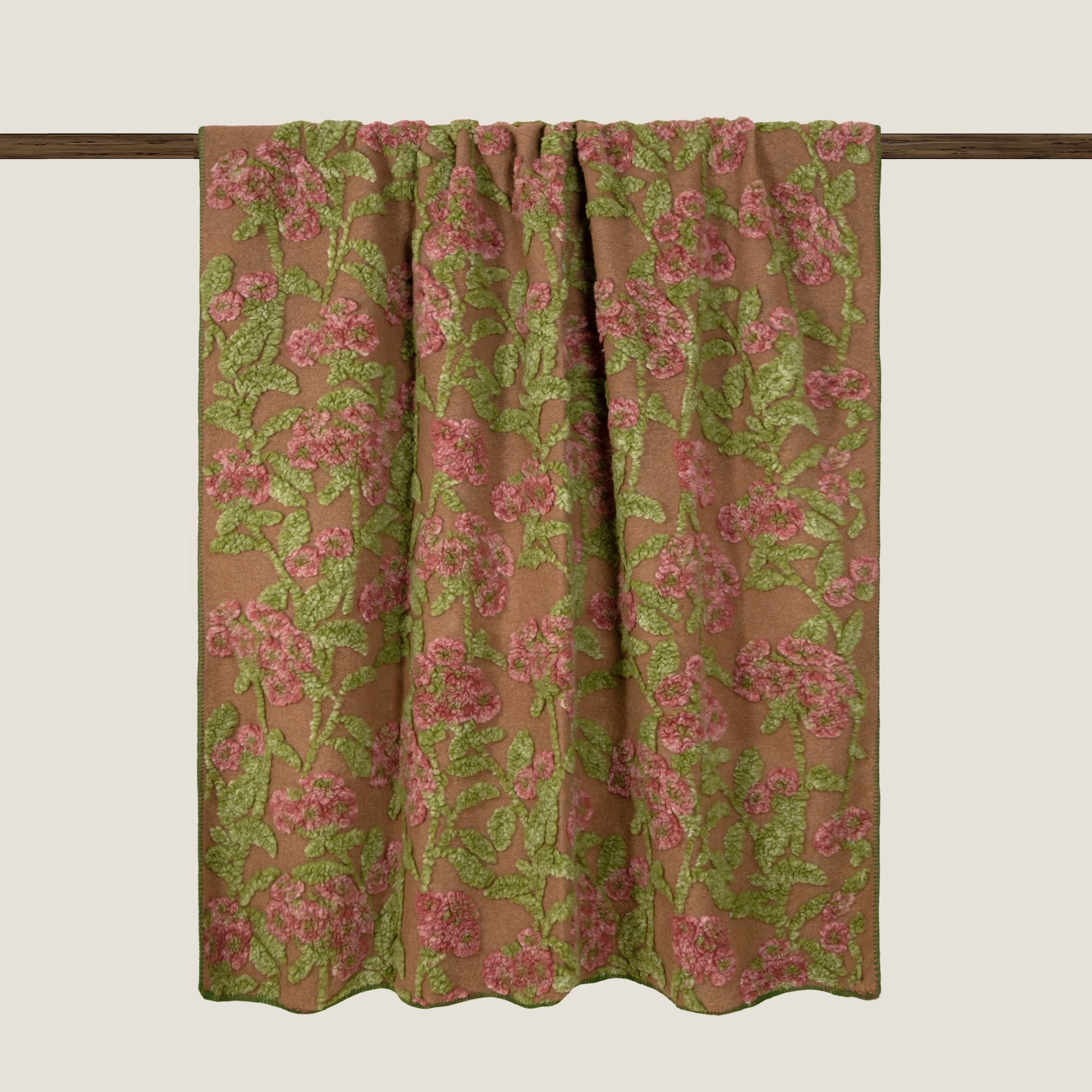 Beige boiled wool light weight throw with a green and pink floral design finished with a green blanket stitch edge.