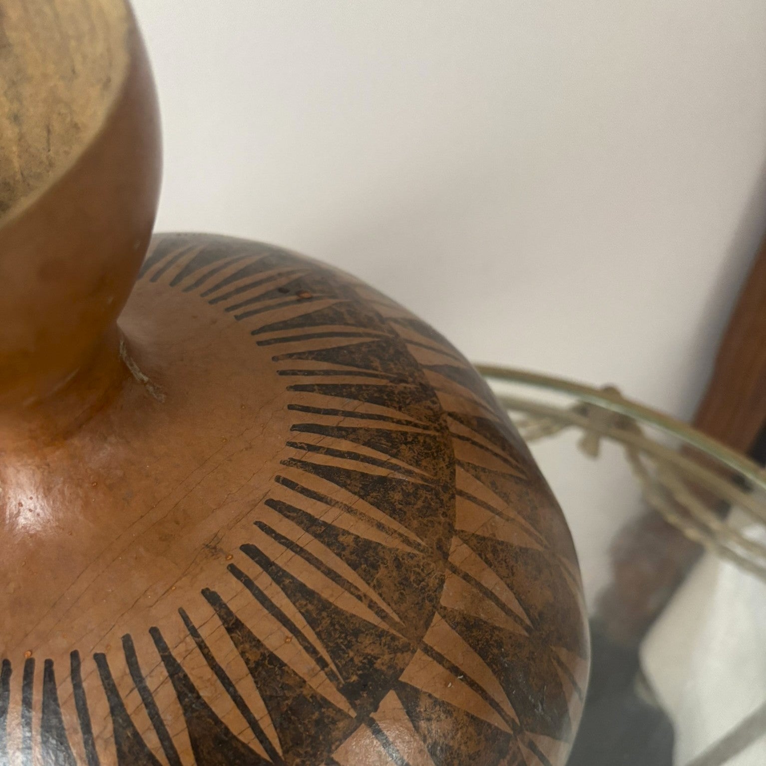 Tribal used gourd decorated with black geometric patterns.