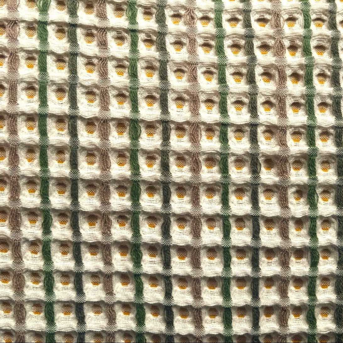 Honeycomb waffle bedspread with green, beige and mustard colour woven throughout.