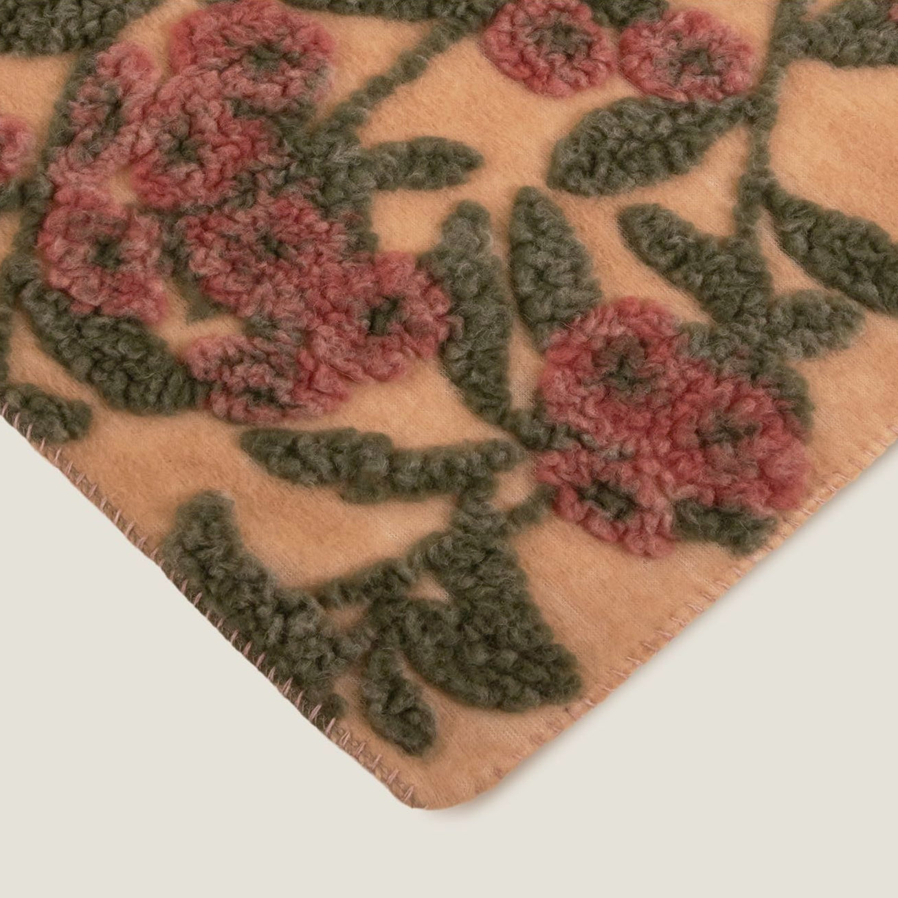 Beige boiled wool throw in burgundy with old rose pattern finished with a beige blanket stitching.