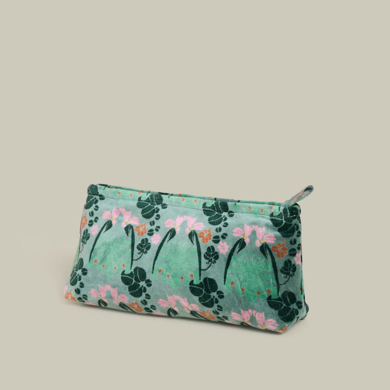 A small zippered pouch with a green floral and leaf pattern, featuring pink flowers and dark green leaves, set against a solid light beige background.