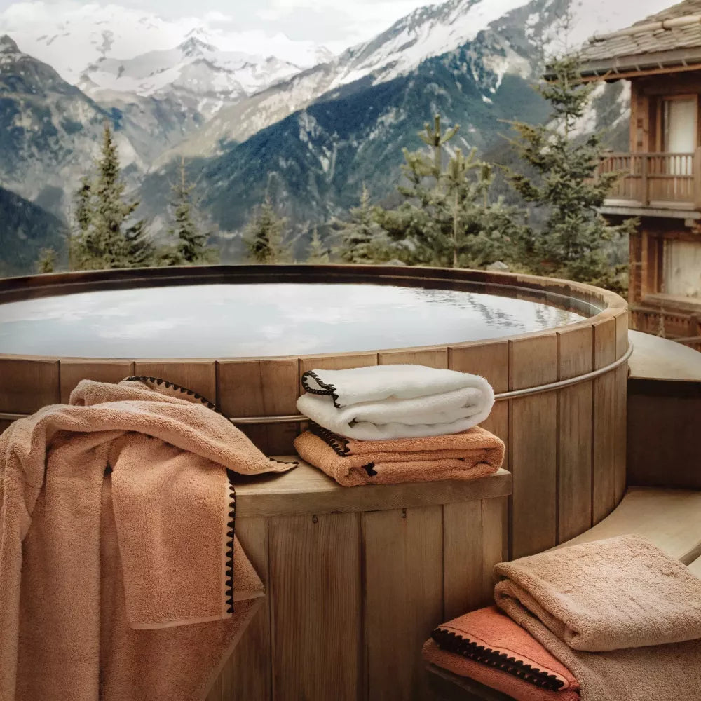 Cotton embroidered edge towels stacked next to a hot tub.