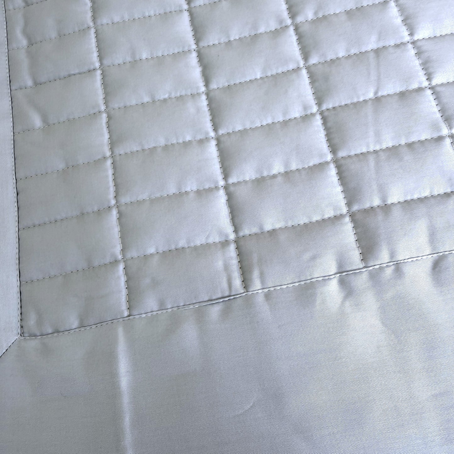 Close up of sion blue quilted bedspread showing the quilted stitching.
