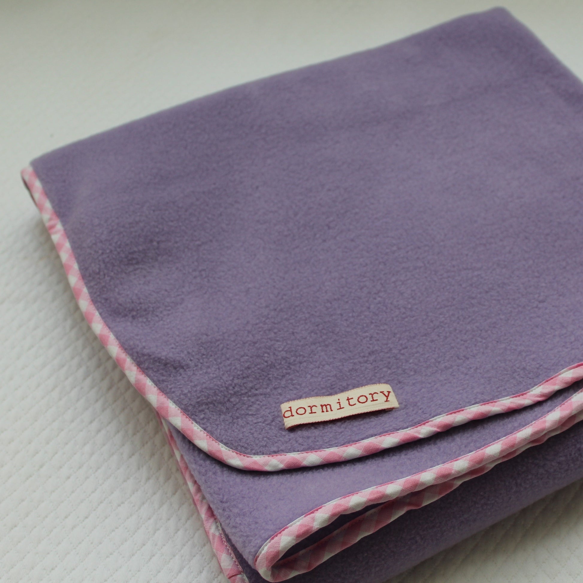 Purple blanket with pink trim and 'dormitory' label on a light background