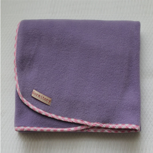 Purple blanket with pink checkered edge on a white background