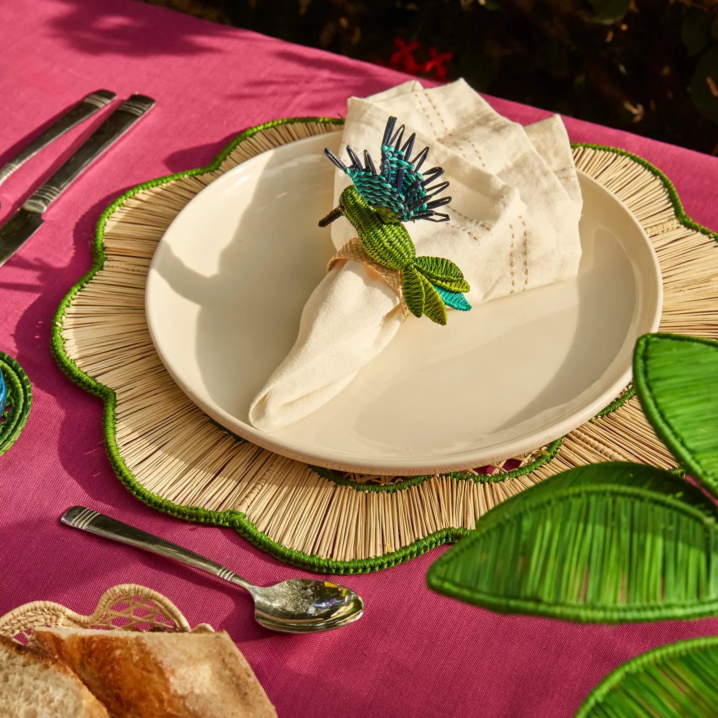 Green and blue humming bird napkin ring presented on a plate.