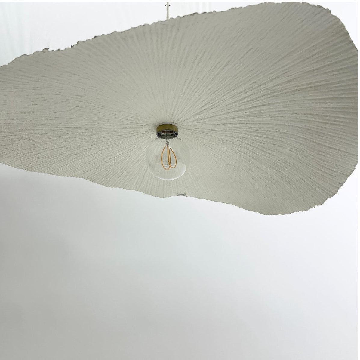 White paper wave pendant light shown hung up on the ceiling.