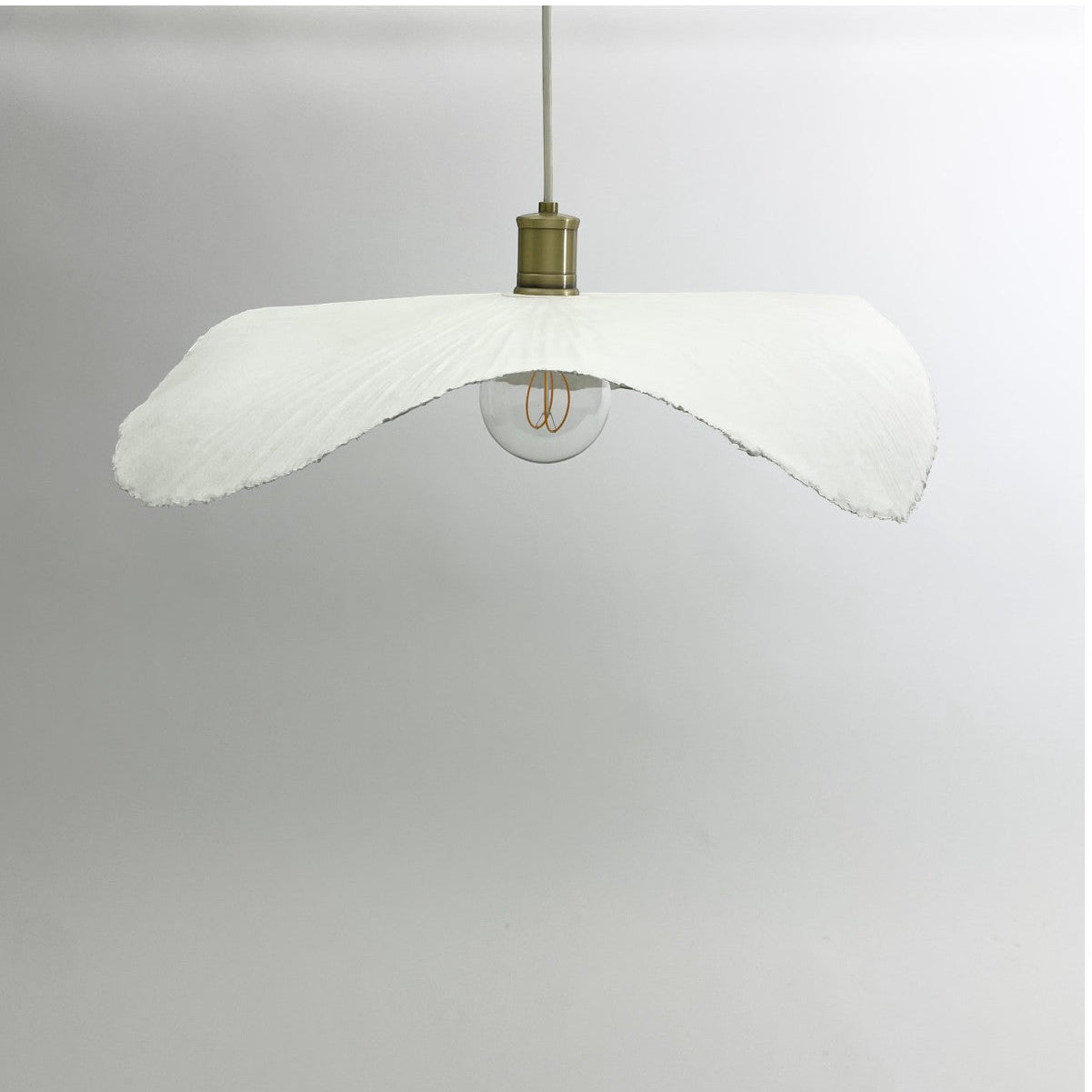 White wave paper pendant shown suspended from the ceiling.