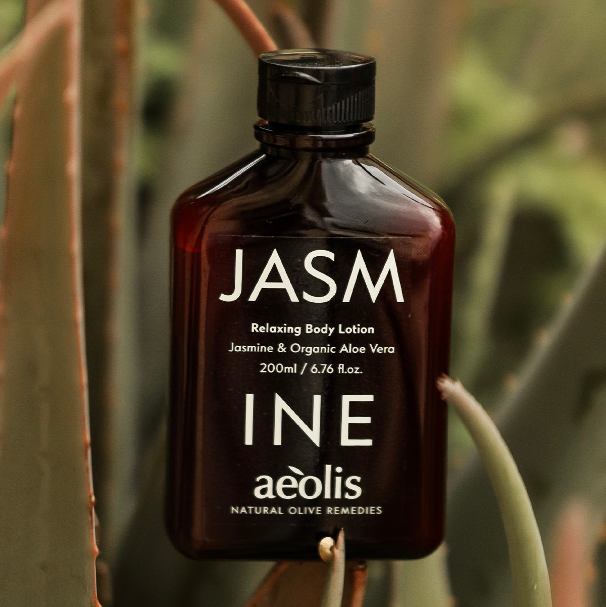 A dark amber bottle of aéolis JASM Relaxing Body Lotion with a black cap, set against a natural background of aloe vera leaves. The text 'Relaxing Body Lotion' is written at the bottom.