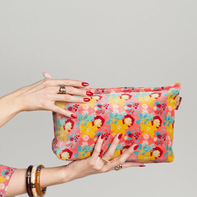 Neon pink velvet washbag with a yellow, blue and red floral pattern.