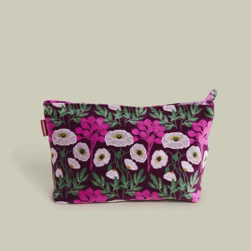 A rectangular zippered pouch with a dark purple velvet-like fabric covered in a pink, white, and green floral pattern, shown on a solid light beige background.