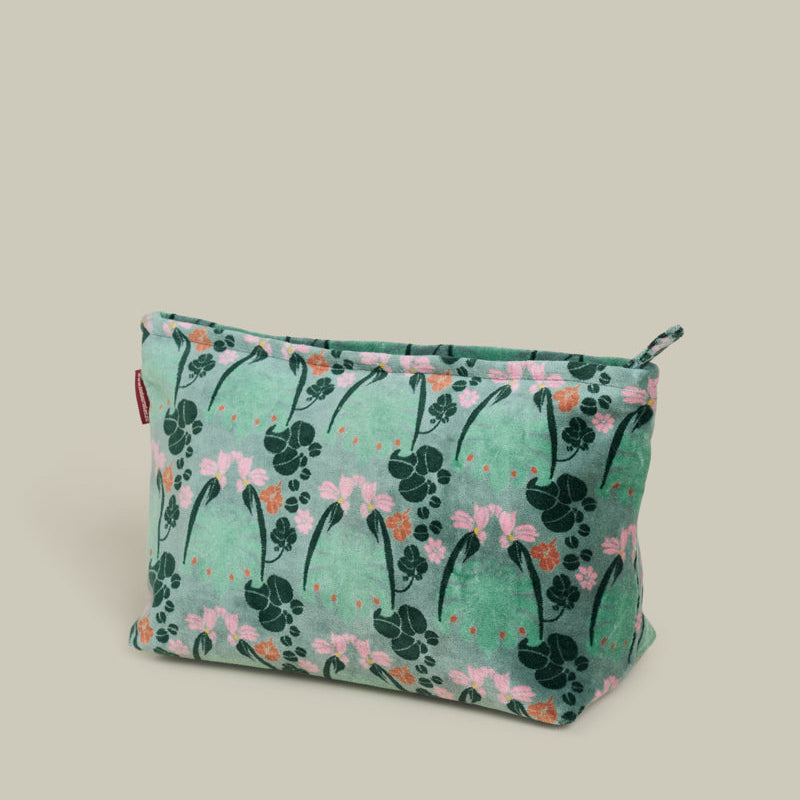 A rectangular zippered pouch with a green floral and leaf pattern, featuring pink flowers and dark green leaves, set against a solid light beige background.