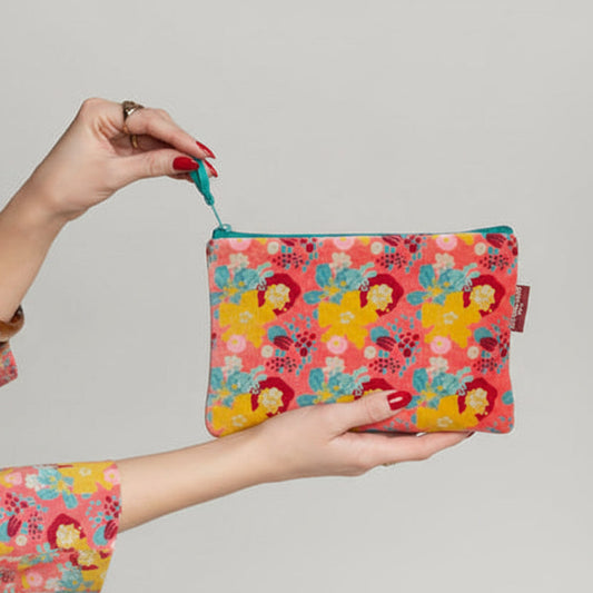 Neon pink velvet pouch with a yellow, blue and red floral pattern.