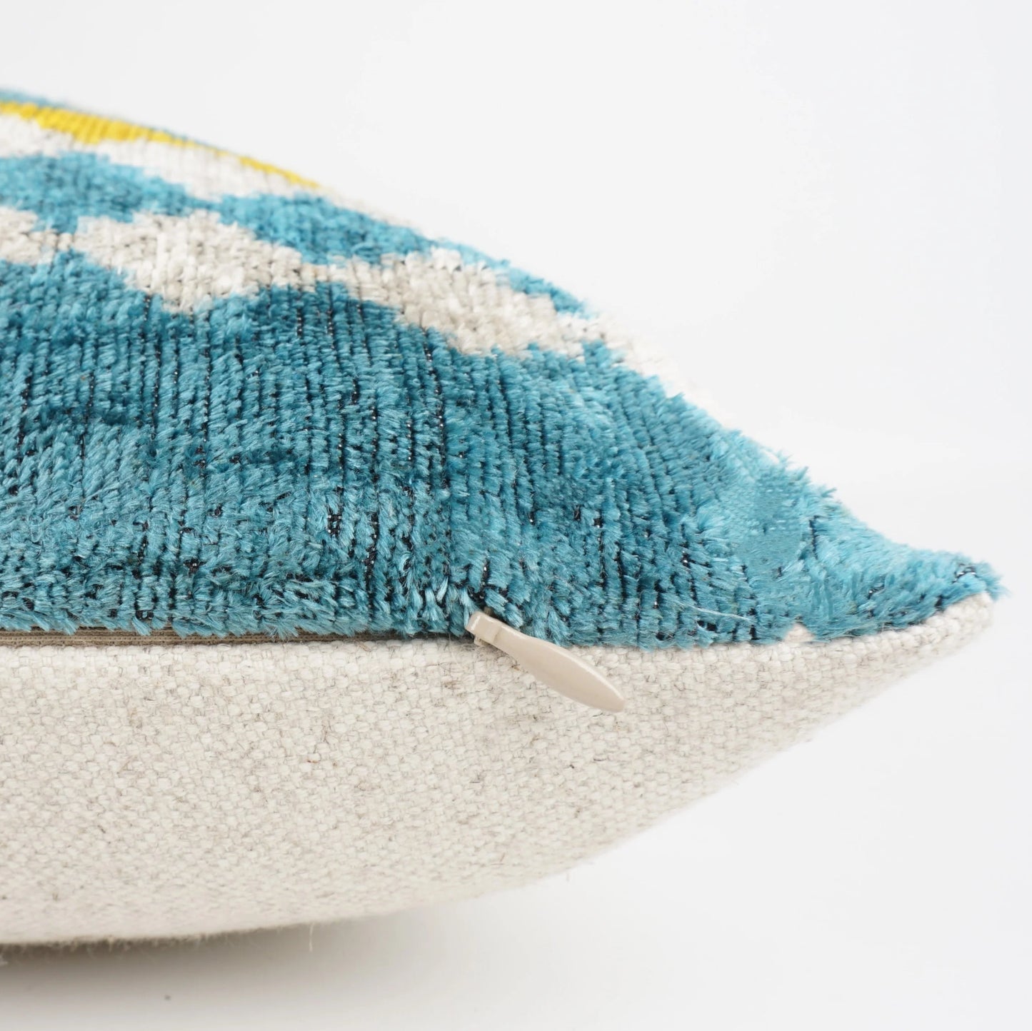 Turquoise and yellow velvet lumber cushion showing the linen backing of the pillow.