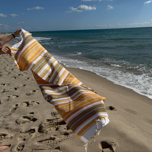 Cotton fouta stripe beach towel blowing in the wind on a beach.