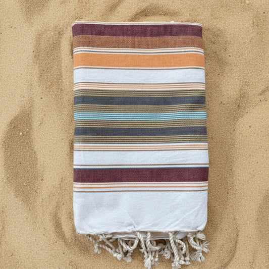 Burgundy, orange and white striped beach towel with a fringed edge.