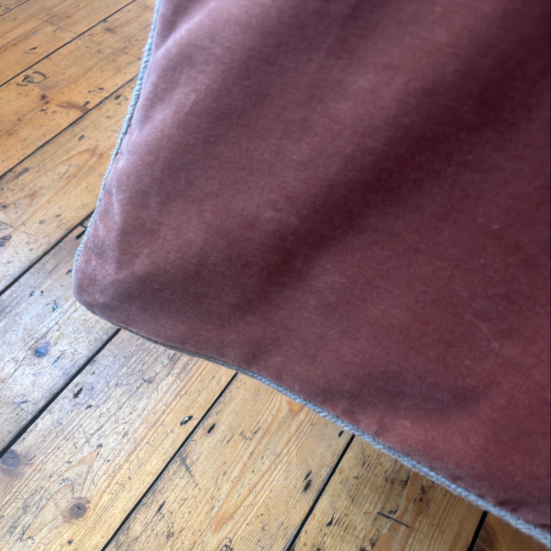 Corner of moccacino pink bed quilt with a white corded edge.