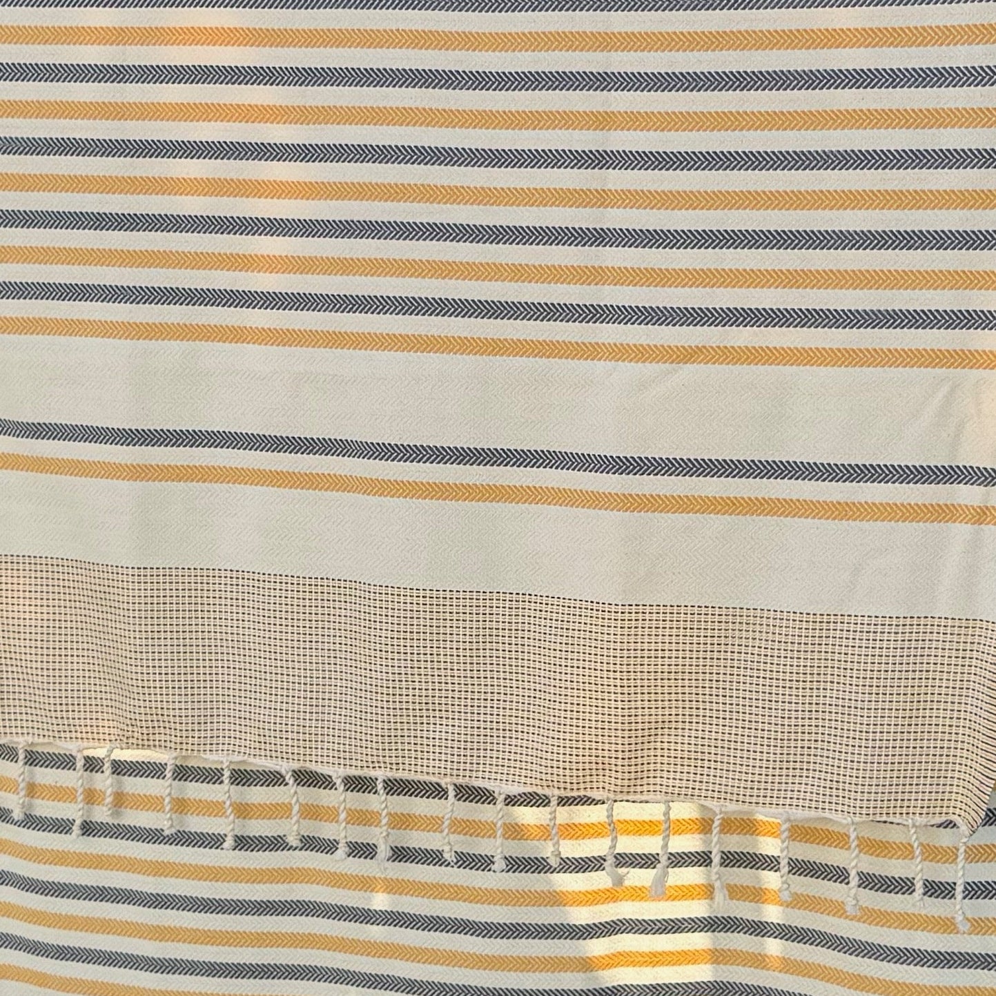 Yellow, blue and white striped beach towel.