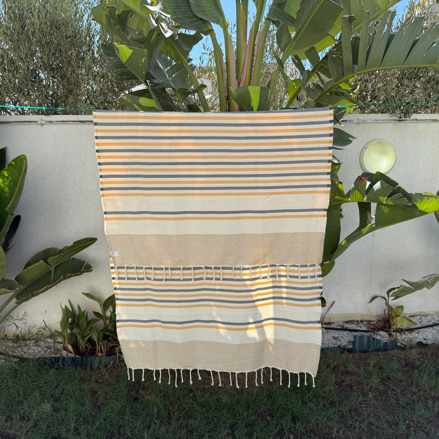 Yellow and navy striped beach towel with a fringed edge.