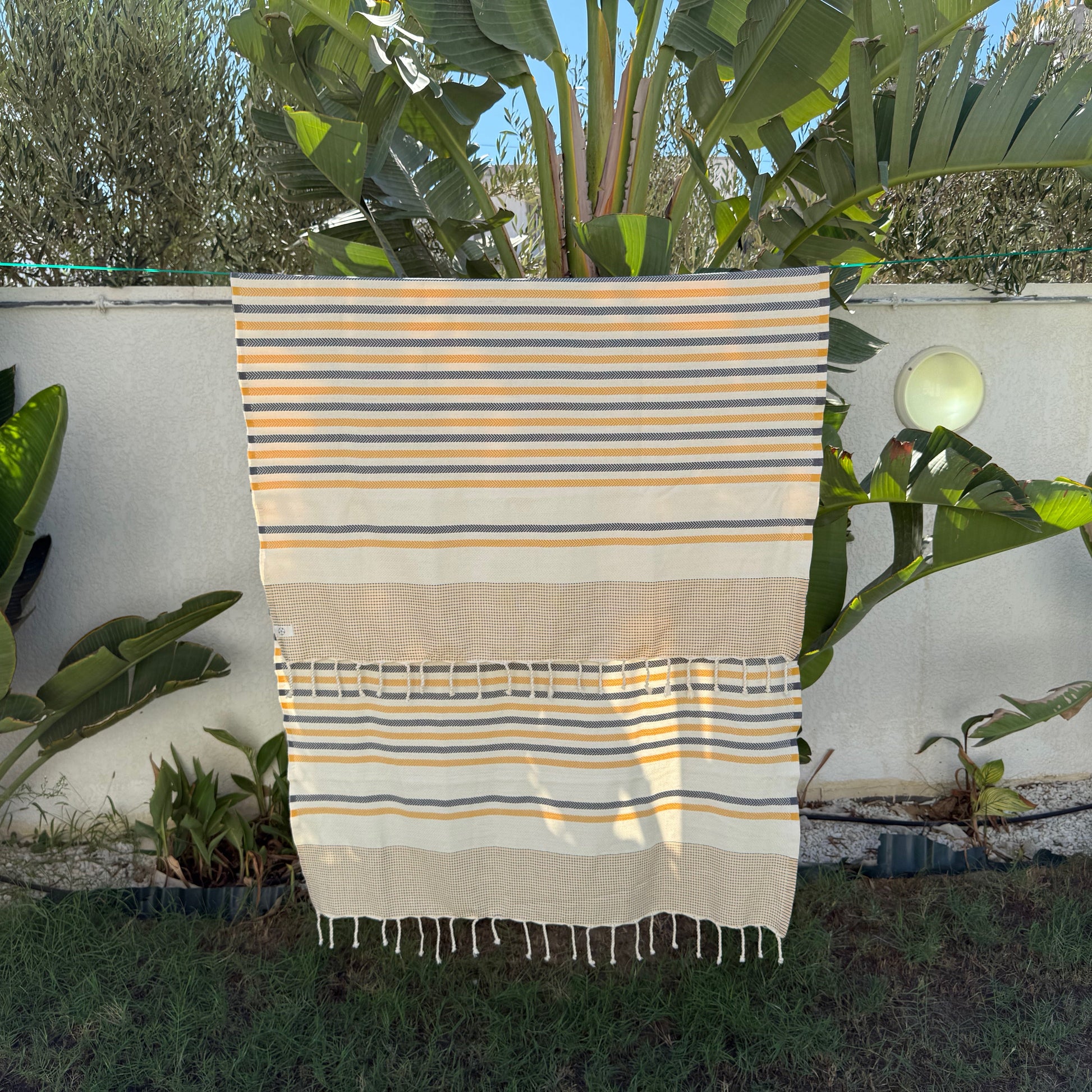 Yellow and navy striped beach towel with a fringed edge.