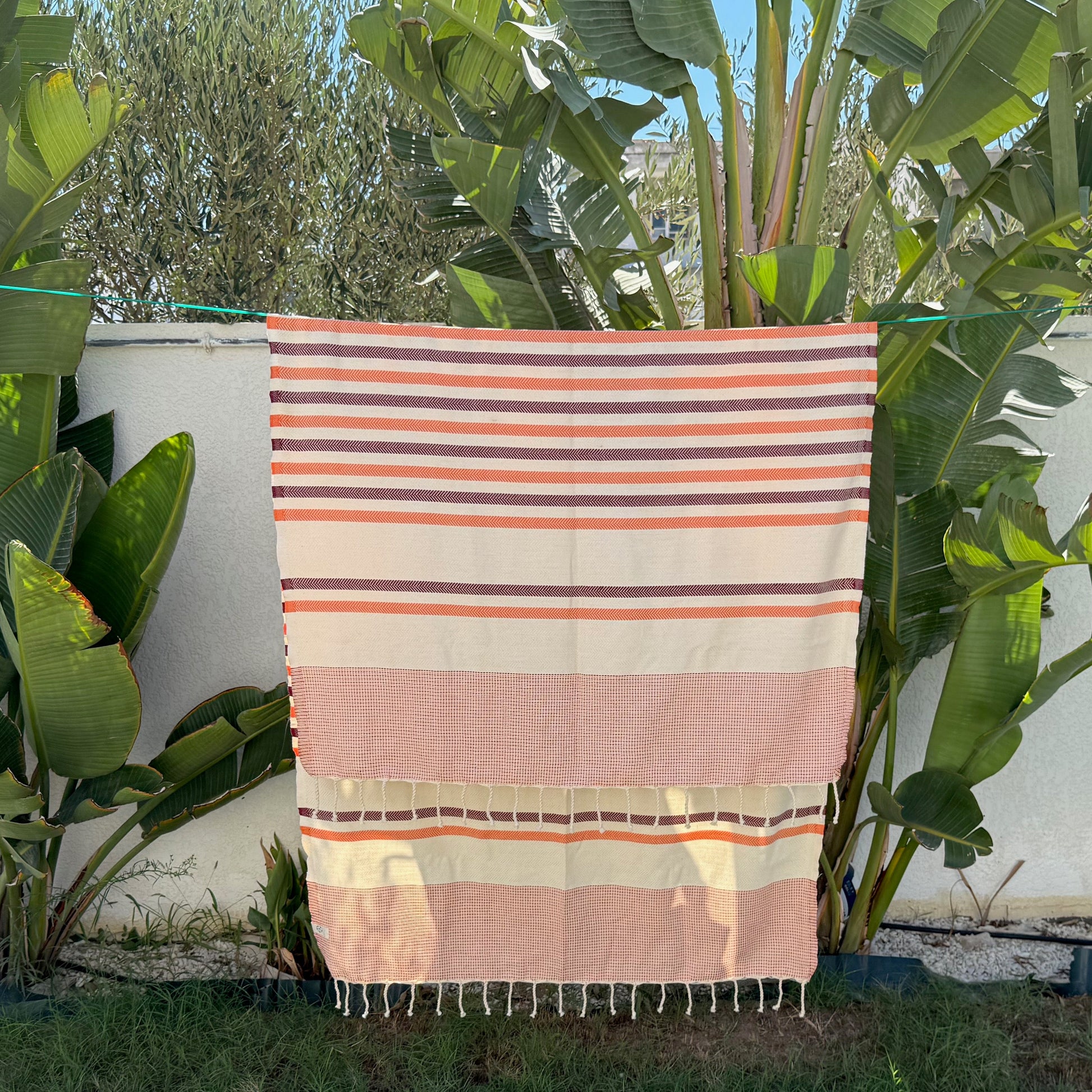 Orange, burgundy and white striped beach towel.
