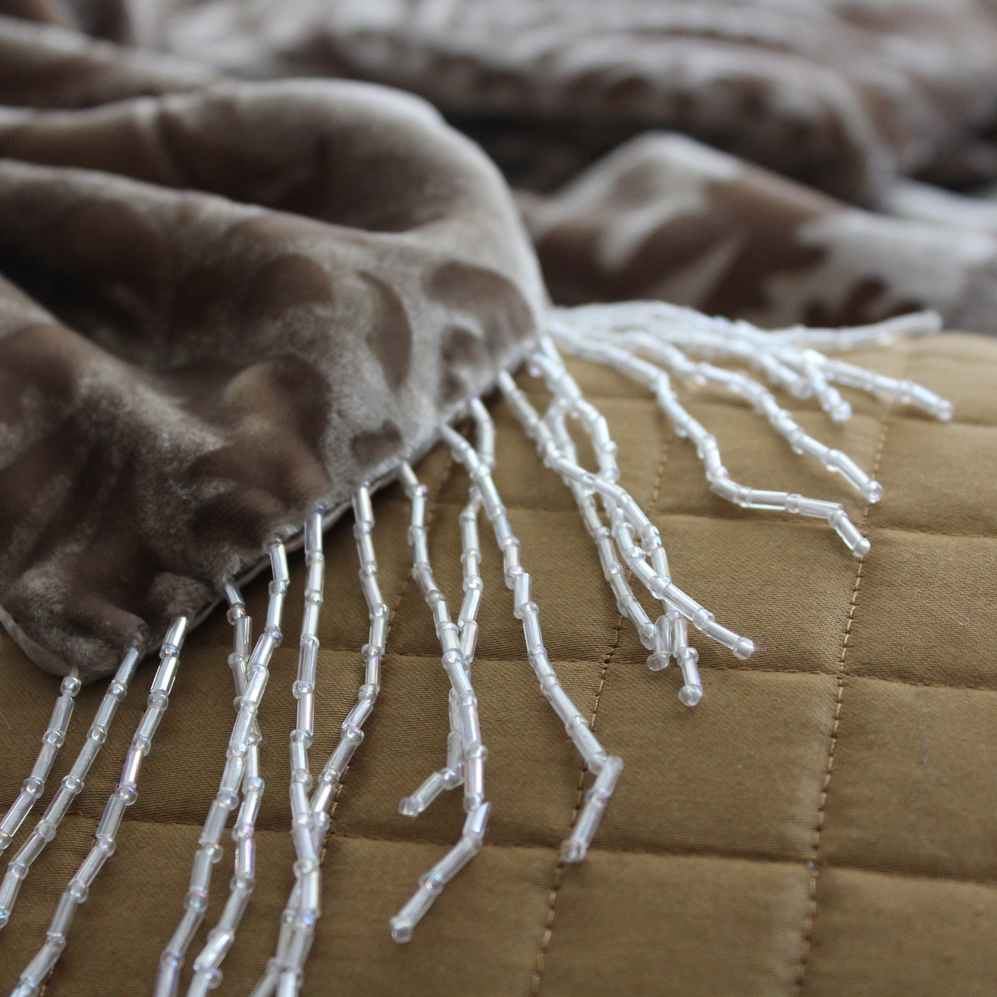 Close up of beaded fringed cushion showing the fringed detailing.