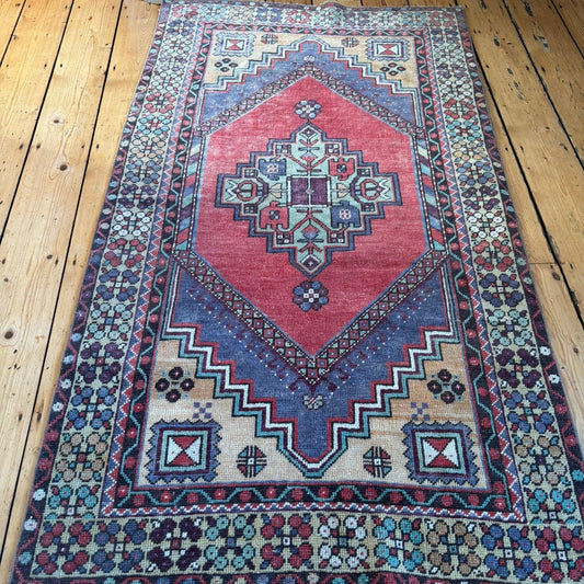 Vintage turkish rug with red, blue and yellow traditional turkish patterns.