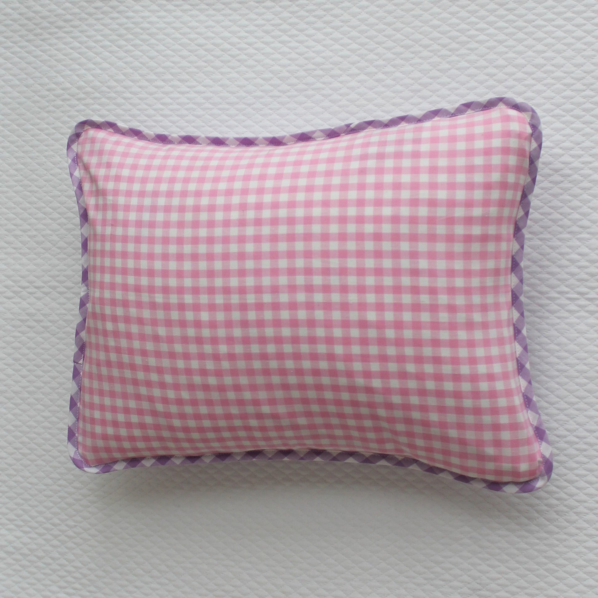 Pink checkered pillow with purple trim on a light gray background