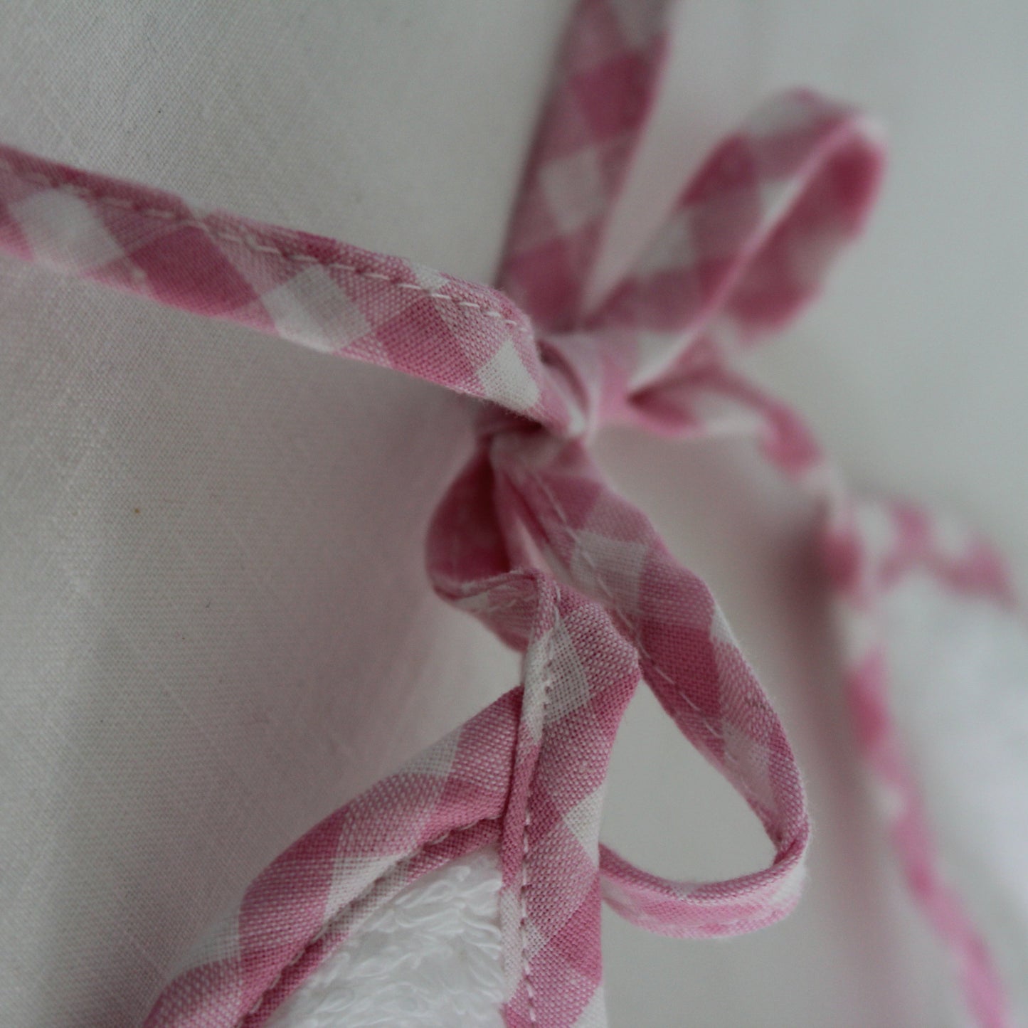 Close-up of pink and white checkered ribbon tied in a bow on a light background