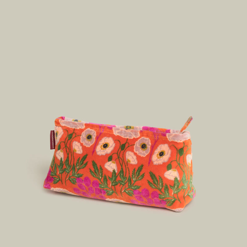 A small zippered pouch with a vibrant orange background and a floral pattern featuring pink, white, and green embroidered poppies, set against a solid light gray background.