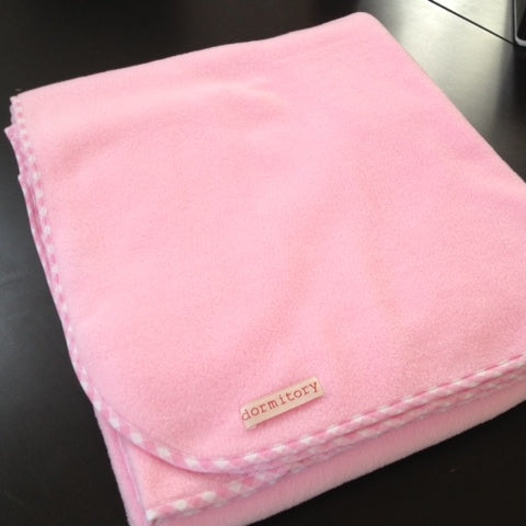 Pink blanket with a 'dormitory' label on a dark surface