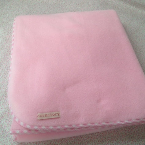 Pink blanket with a 'dormitory' label on a textured surface