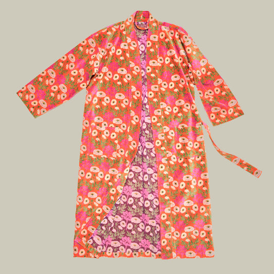 A long-sleeved open-front robe with a vibrant pink, orange, and green floral print, featuring a matching tie belt, laid flat against a solid light gray background.