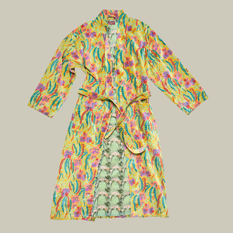 A long-sleeved cotton robe with a vibrant yellow base, featuring a multicolor floral and paisley print in pink, green, and blue, complete with a matching tie belt.