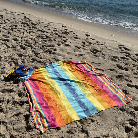 Rainbow striped beach towel with a fringed edge.