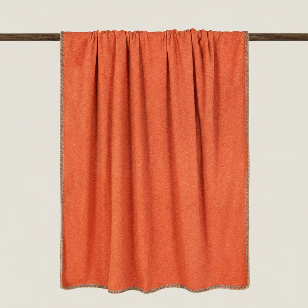 Orange soft bamboo throw displayed hanging over a rail.