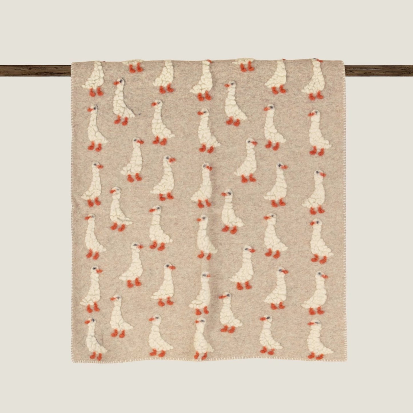 Beige boiled wool baby blanket patterned with duckings.