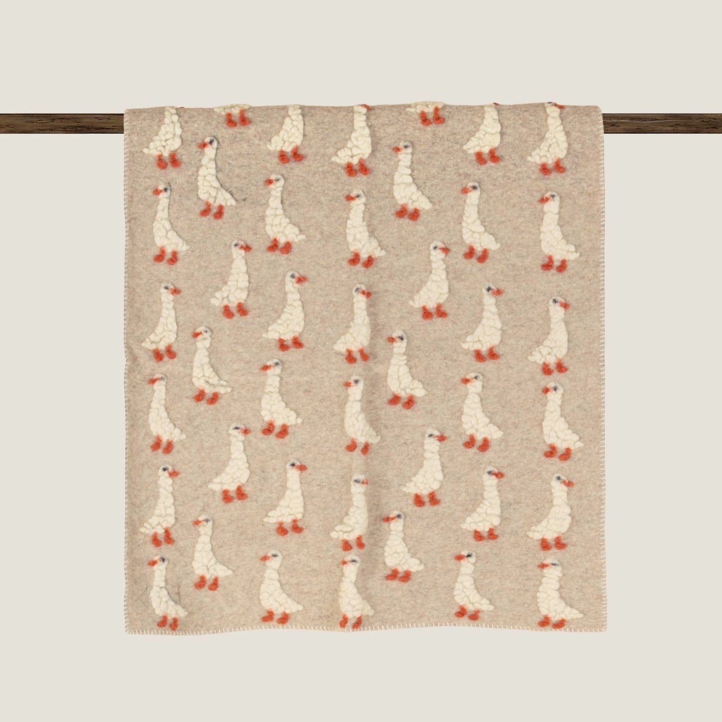 Beige boiled wool baby blanket patterned with duckings.