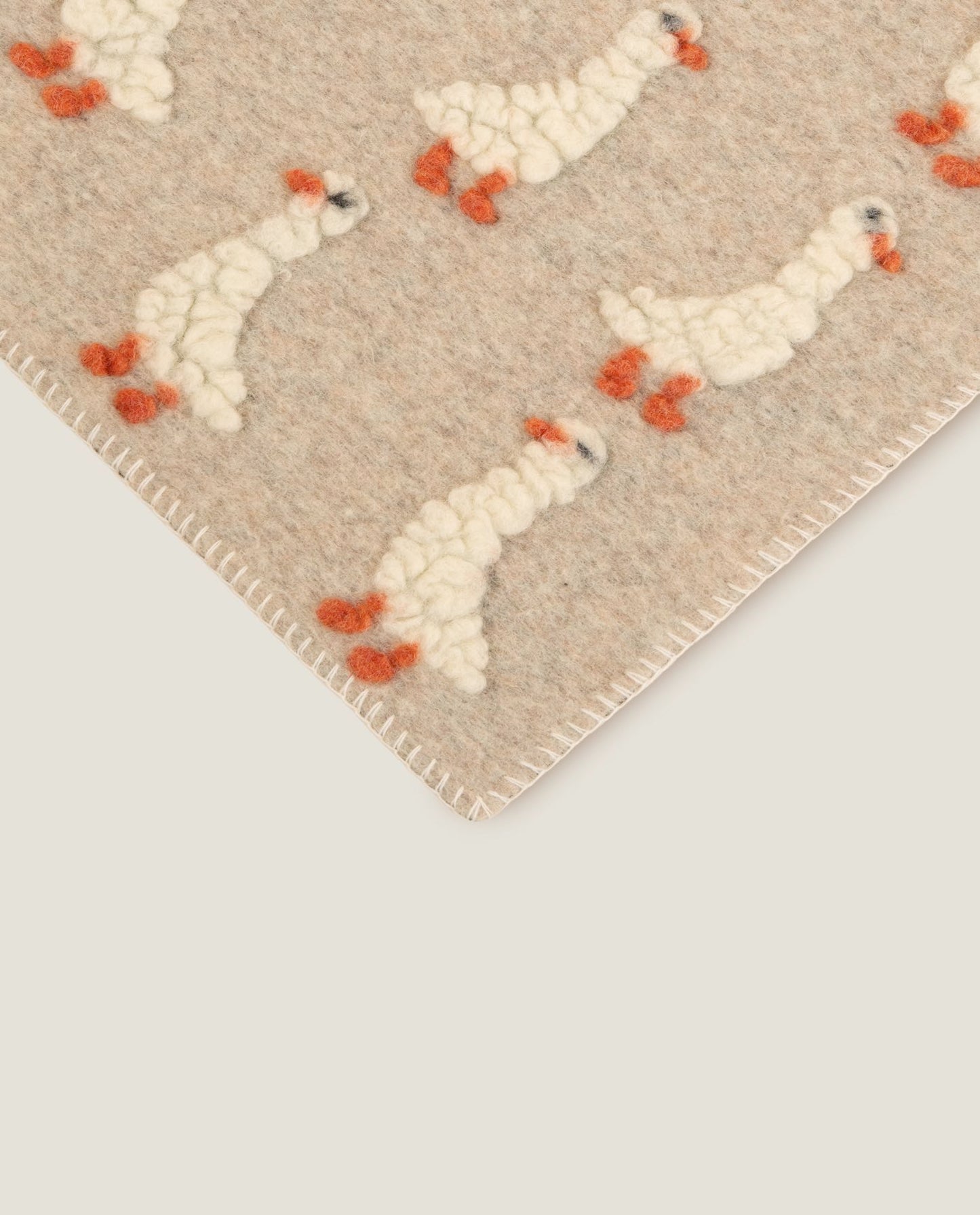 Beige wool blanket with ducking motifs patterned throughout, finished with a white blanket stitched edge.