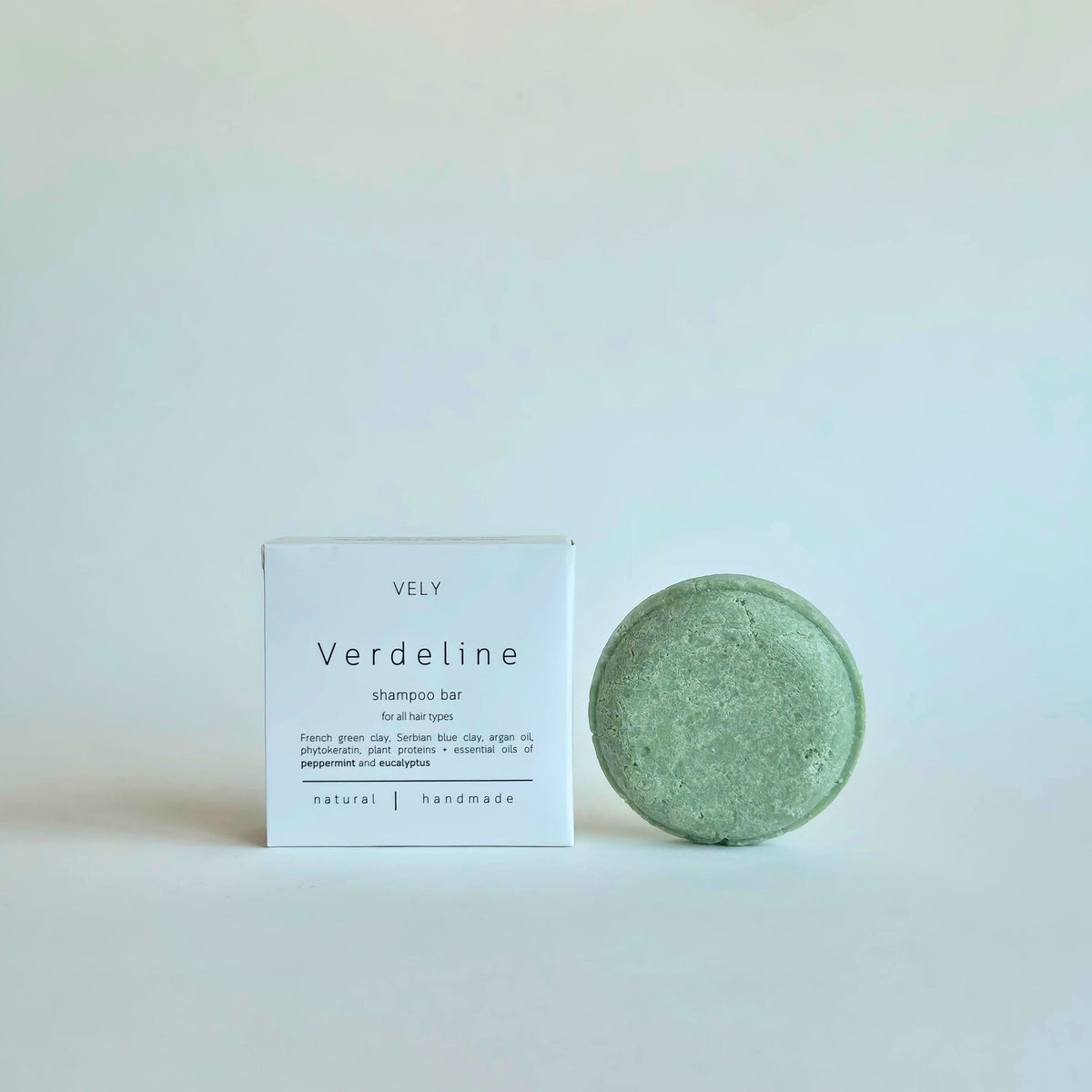 A round, light green shampoo bar next to its white packaging box labeled 'VELY Verdeline shampoo bar' on a clean, light off-white background.
