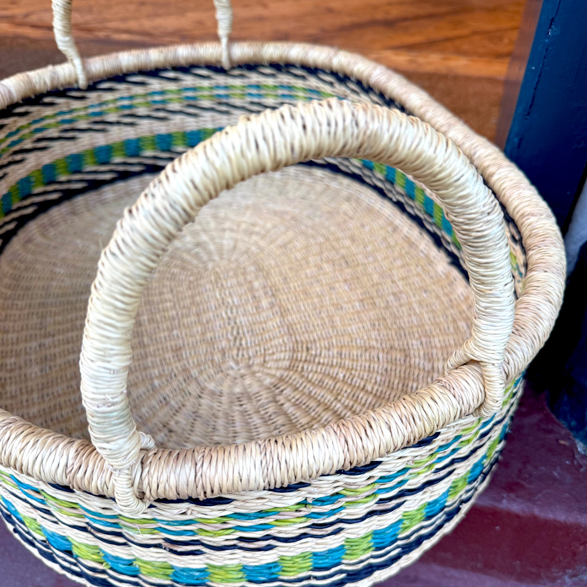 Woven tray with blue and green patterns focus on the woven handle.