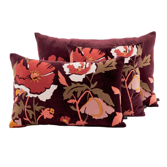 Three decorative throw pillows with a dark burgundy velvet fabric and a large floral pattern in red, pink, white, and olive green, arranged against a plain white background.