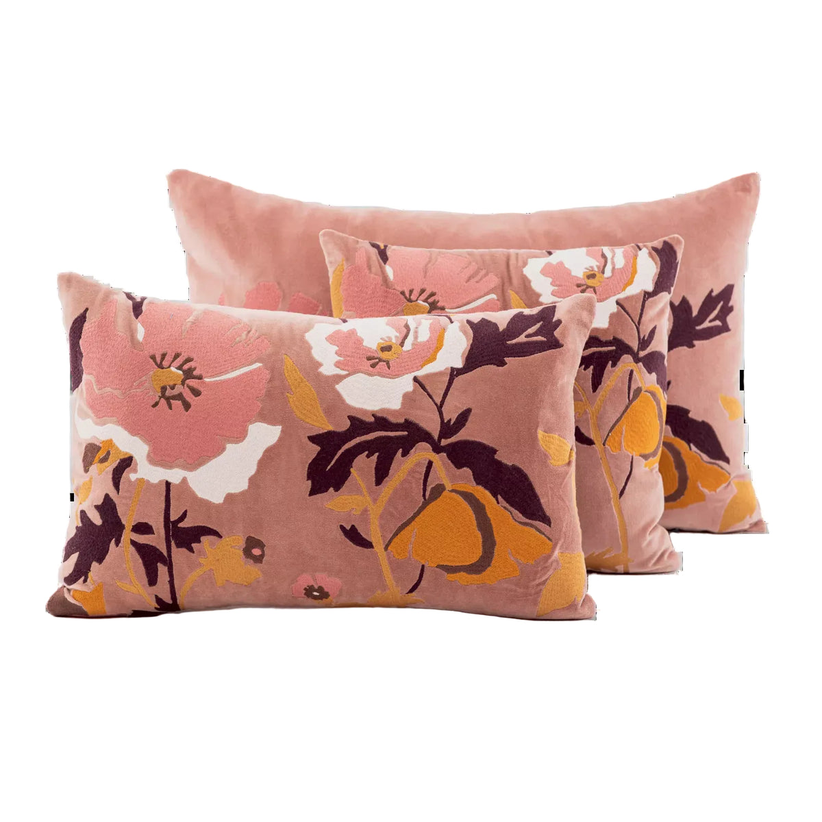 Three rectangular decorative throw pillows in a dusty pink velvet fabric with a large floral print in orange, white, and dark purple, arranged in a layered studio composition on a white background.