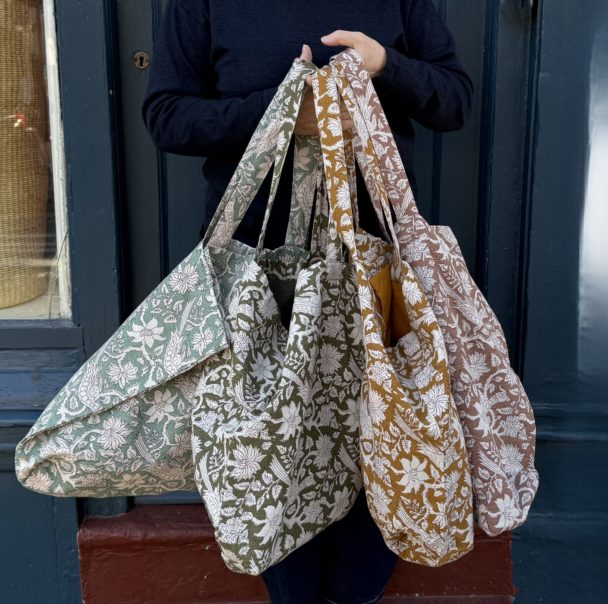 Person holding the range of blockprint market bags in each colour.