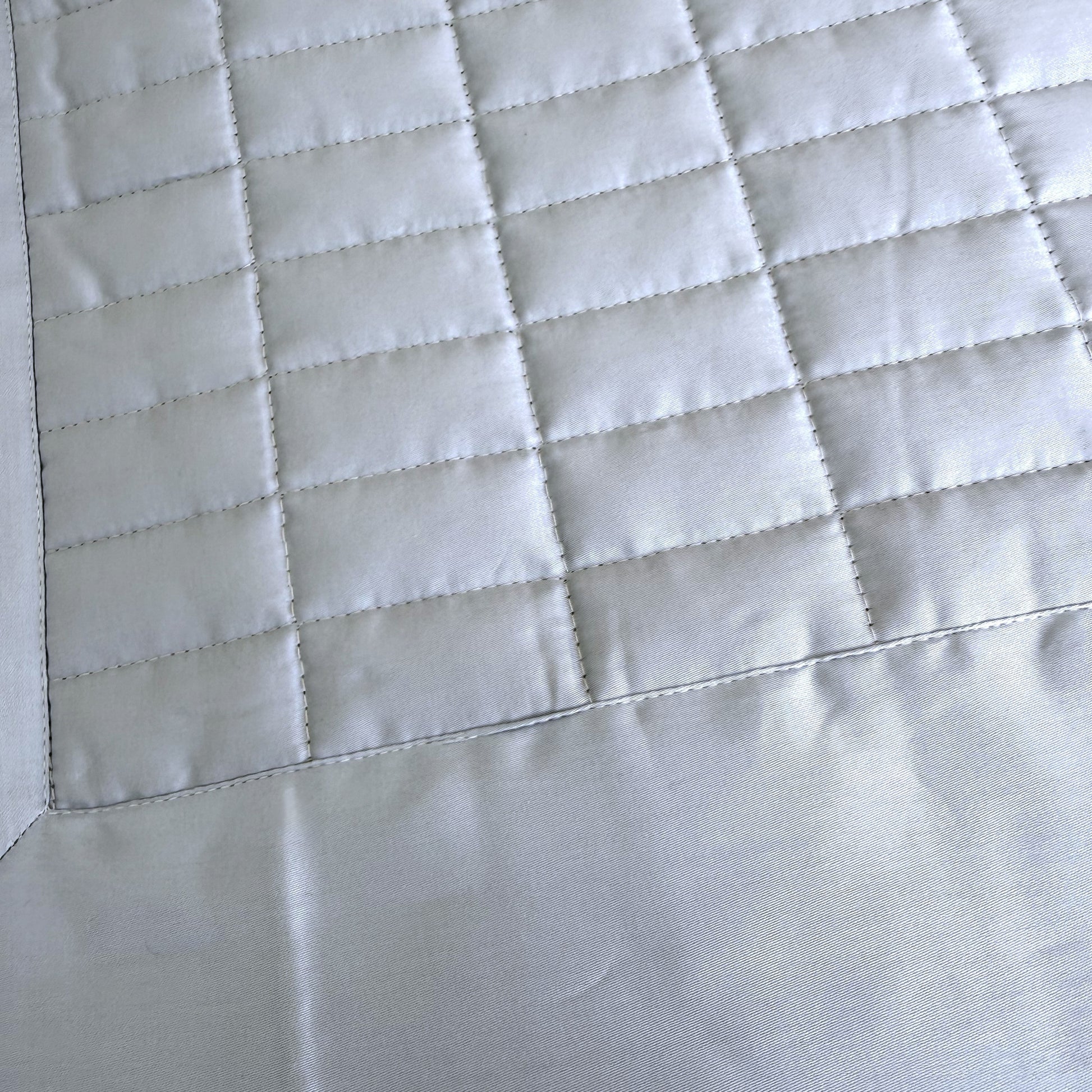 Close up of sion blue quilted bedspread showing the quilted stitching.