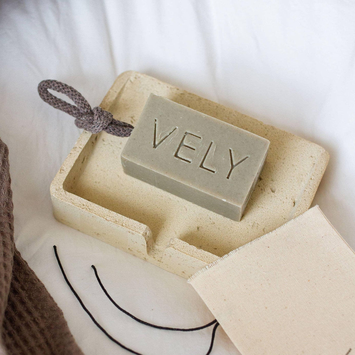 Bar of soap with 'VELY' branding in a box on a soft surface